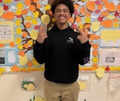 Student stands in front of gratitude tree.