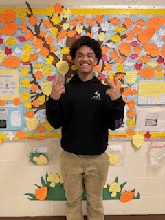 Student stands in front of gratitude tree.